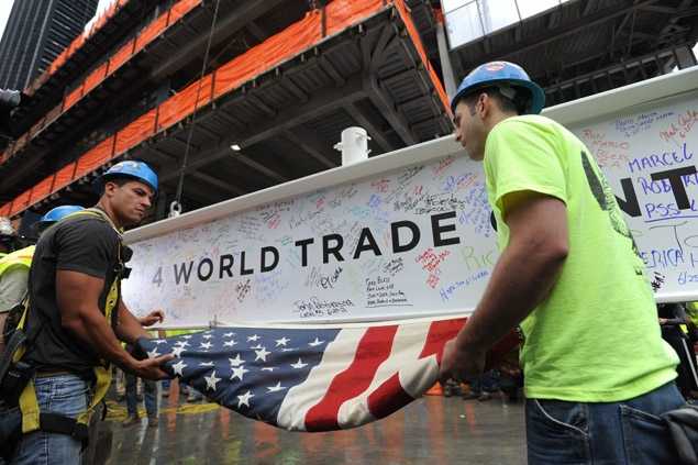 Workers unfurl the American flag from the beam